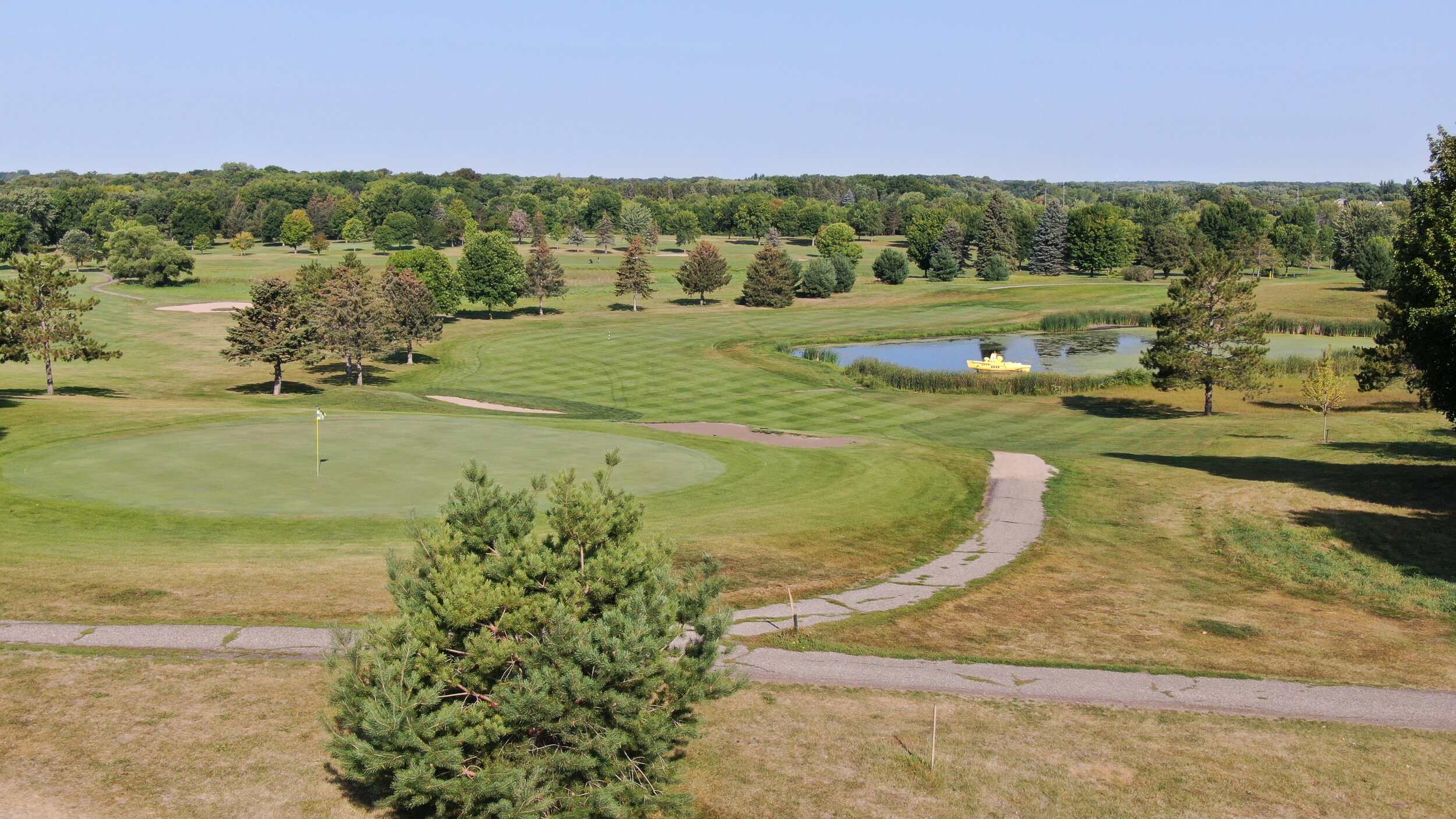Elevated view over a green and cart path toward the pond with the yellow submarine at Montgomery National