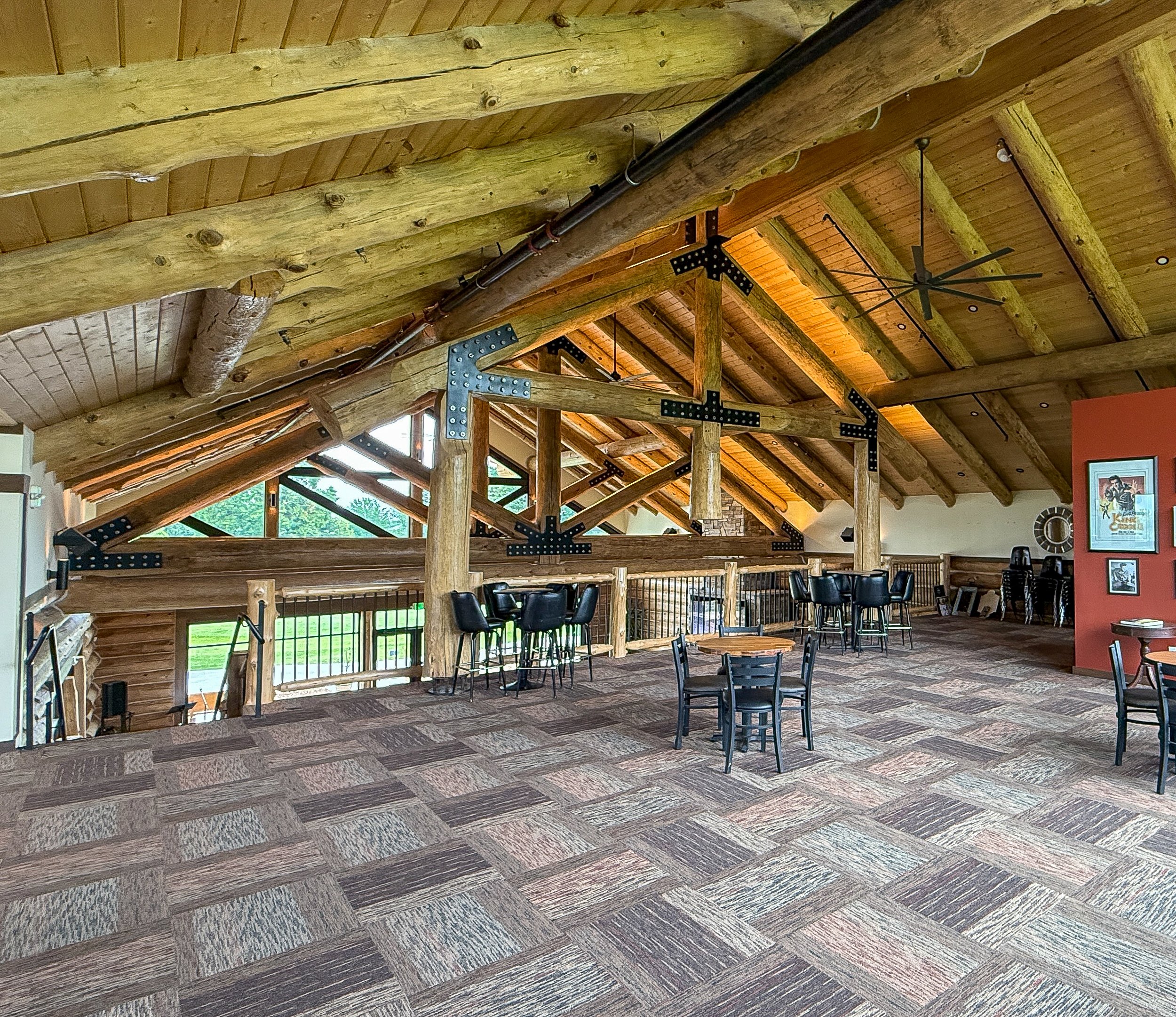 Tables and high-top seating on the clubhouse's upper level under exposed log roof trusses