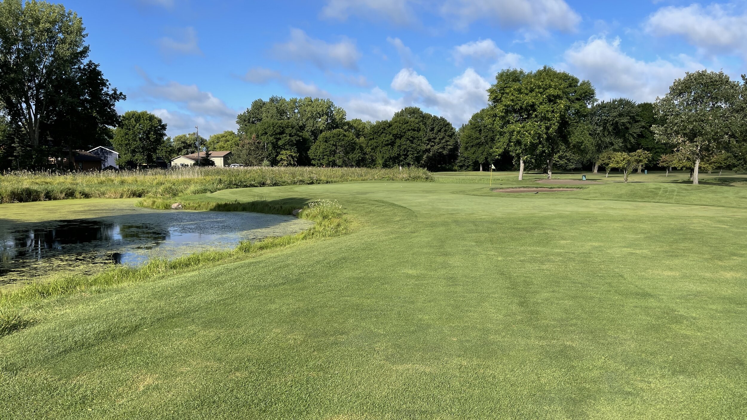 A pond beside the fairway leading to a flagged green at Montgomery National