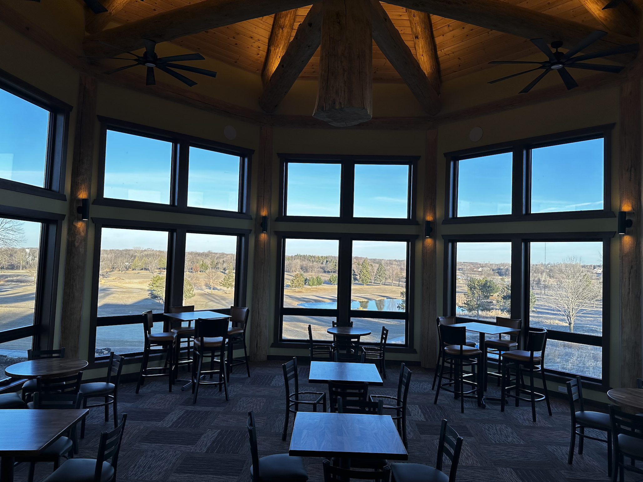 Tables in a windowed room of the clubhouse overlooking the course