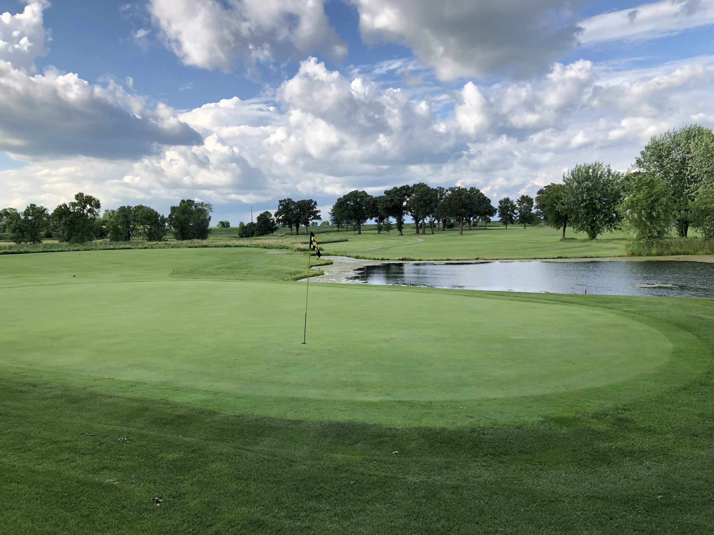 A flagged green with a pond behind it at Montgomery National