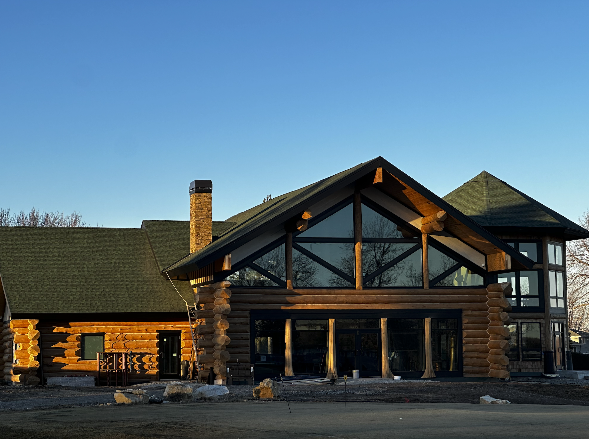 The timber-framed glass front of the log cabin clubhouse in low sun