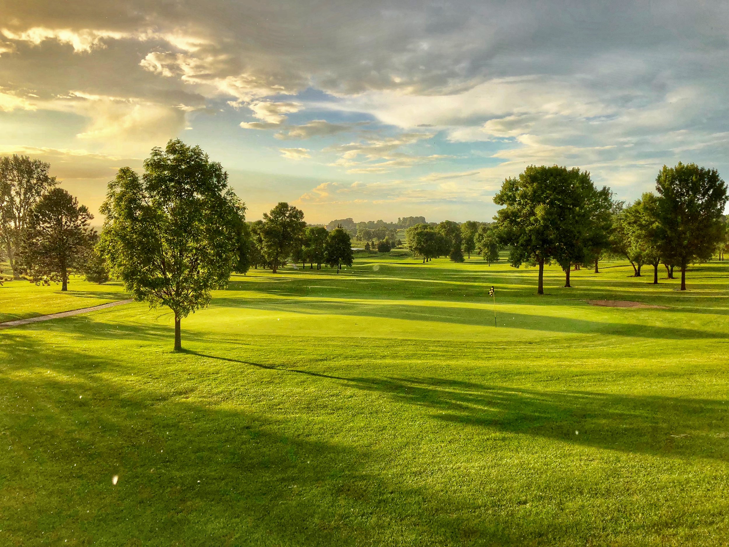 Long shadows across a tree-lined fairway and green in low sun at Montgomery National